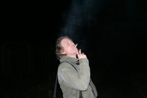 The blue-white haze of cigarette smoke in cold night air, caught in the camera flash